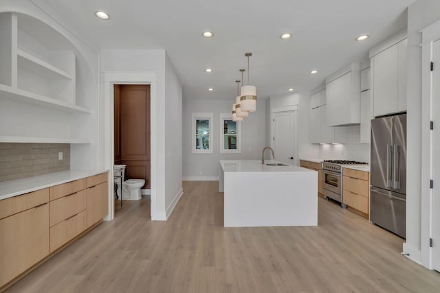 kitchen with modern cabinets, high end appliances, light countertops, and a sink