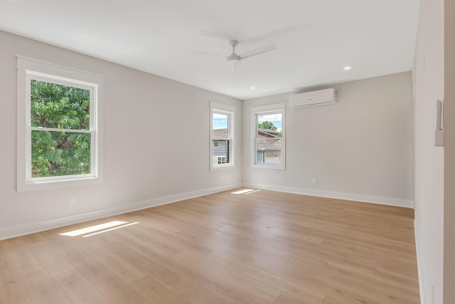 spare room with a ceiling fan, light wood-style floors, baseboards, and a wall mounted air conditioner