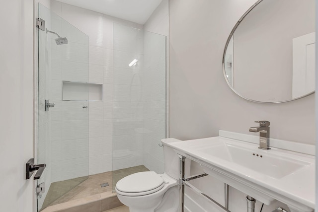 bathroom with a shower stall, toilet, and a sink