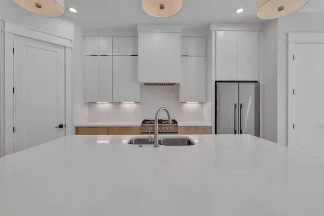 kitchen featuring backsplash, white cabinetry, high end fridge, and sink