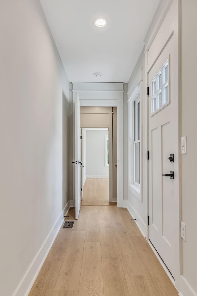 corridor featuring visible vents, baseboards, and light wood-style floors