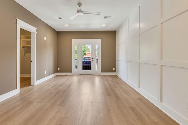 spare room featuring light wood-type flooring, visible vents, and baseboards