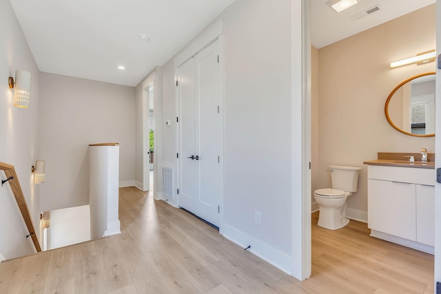 bathroom featuring vanity, wood finished floors, visible vents, baseboards, and toilet