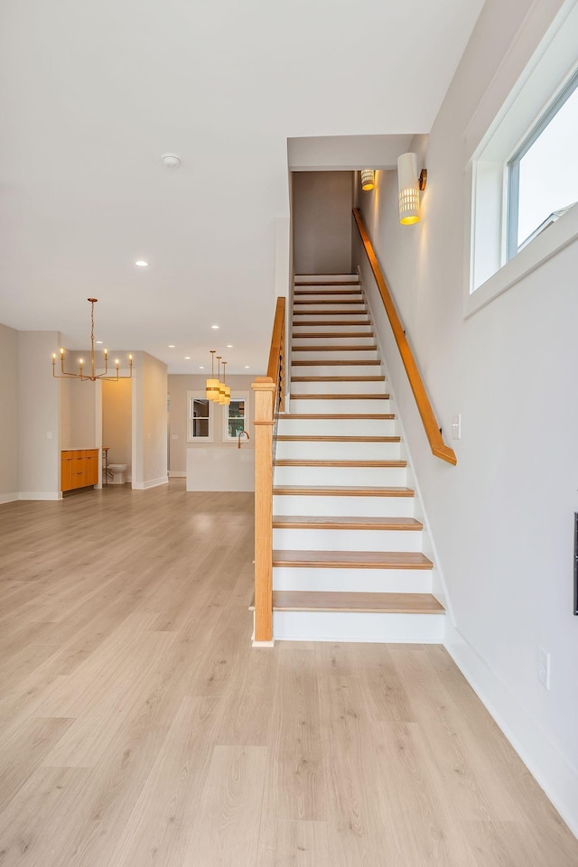 stairs with hardwood / wood-style flooring and an inviting chandelier