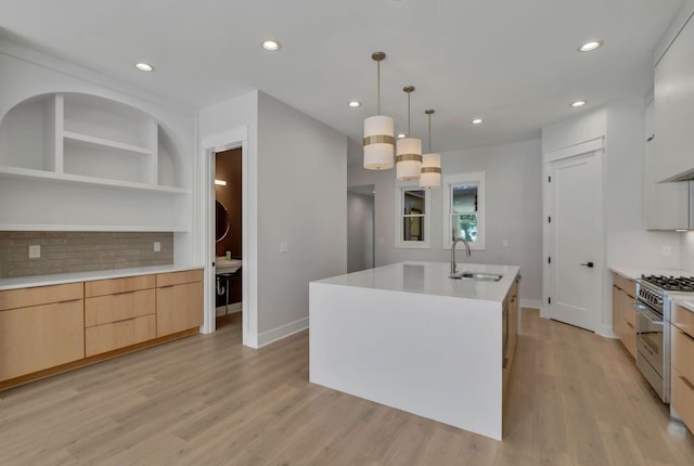 kitchen with high end range, backsplash, a kitchen island with sink, sink, and decorative light fixtures