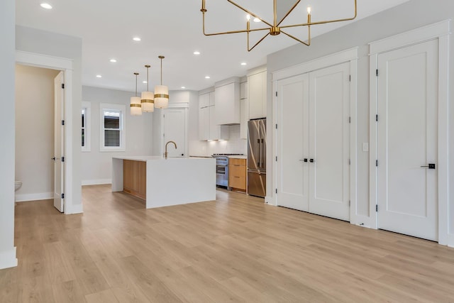 kitchen with premium appliances, light wood-style flooring, light countertops, and a sink