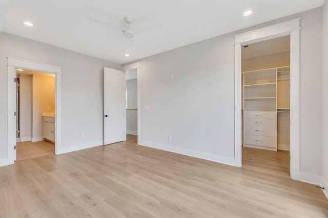 unfurnished bedroom featuring ceiling fan, light hardwood / wood-style floors, a walk in closet, and a closet