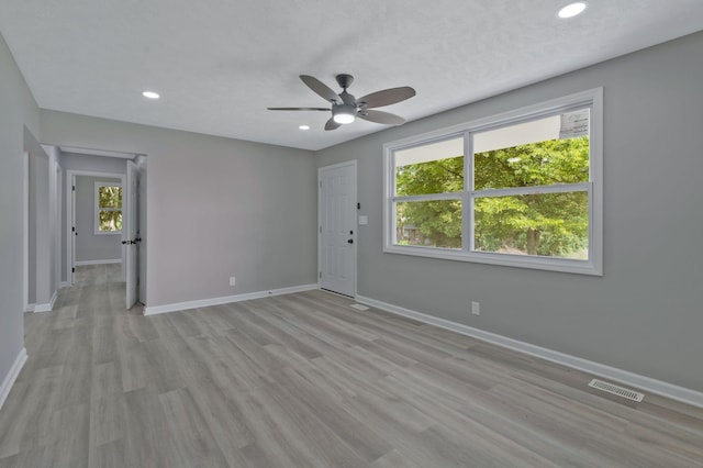 empty room featuring ceiling fan, light hardwood / wood-style flooring, and a textured ceiling