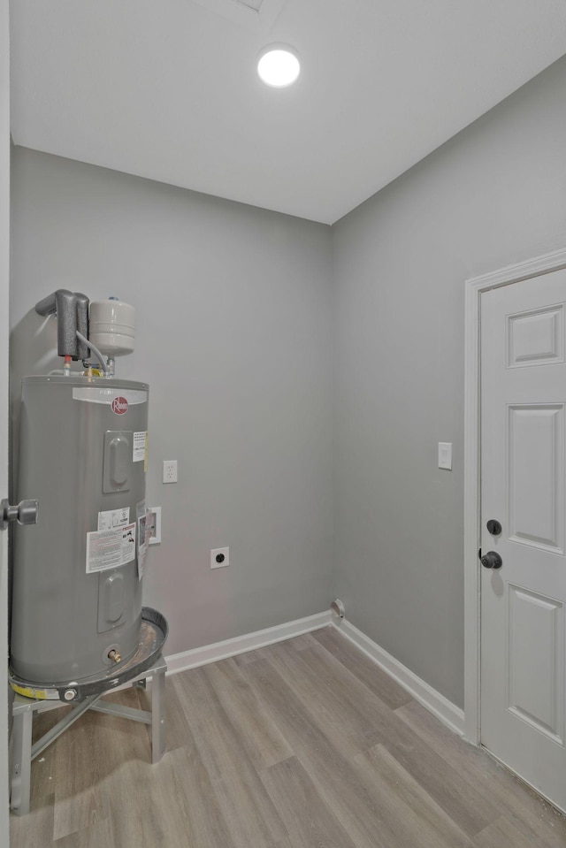 washroom with electric dryer hookup, electric water heater, and light hardwood / wood-style floors