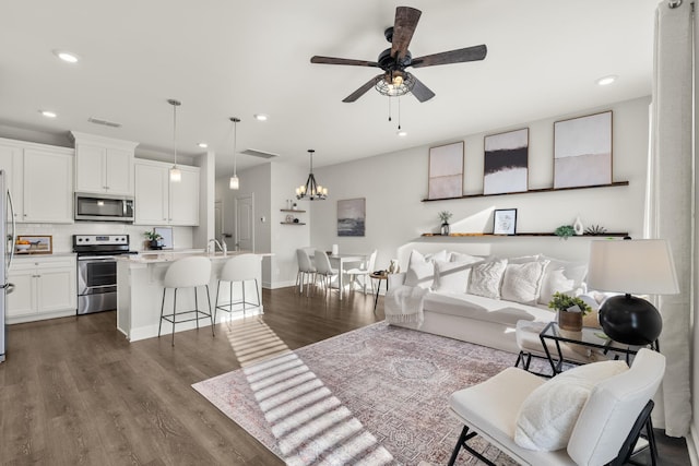 living room with dark wood-type flooring and ceiling fan with notable chandelier