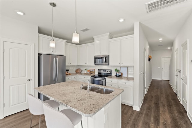 kitchen with a kitchen island with sink, light stone countertops, white cabinetry, and stainless steel appliances