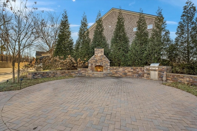 view of patio / terrace featuring area for grilling, a grill, and an outdoor stone fireplace