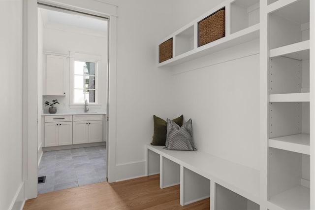 mudroom featuring light hardwood / wood-style floors, built in features, and sink