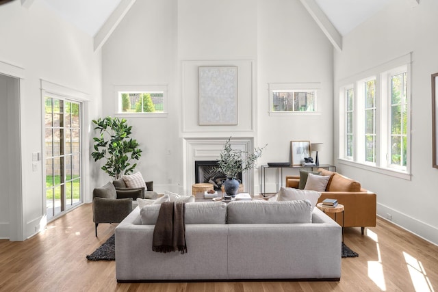 living room with beam ceiling, light hardwood / wood-style flooring, and high vaulted ceiling