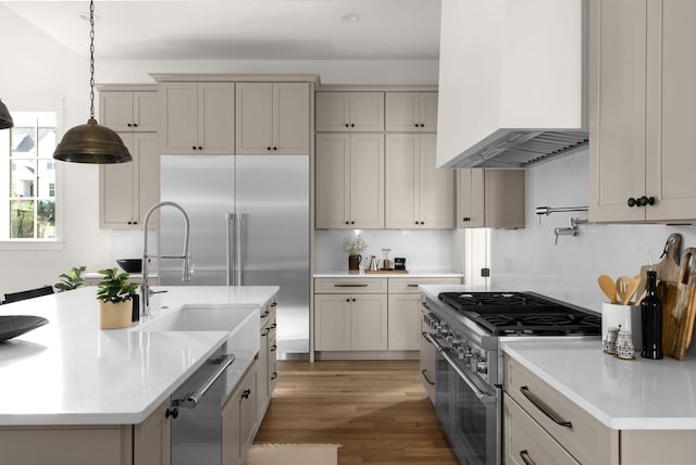 kitchen featuring wall chimney exhaust hood, backsplash, hardwood / wood-style floors, pendant lighting, and high quality appliances