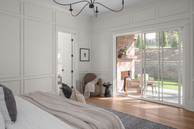 bedroom with access to exterior, hardwood / wood-style floors, and a chandelier