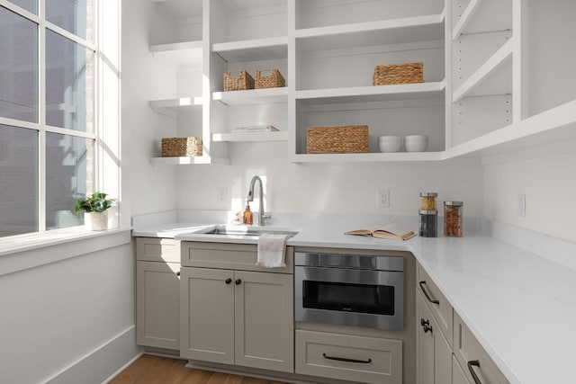 kitchen with gray cabinetry, sink, and light hardwood / wood-style flooring