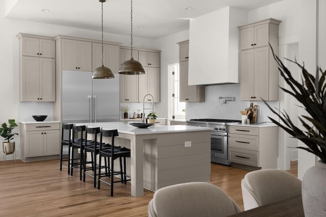 kitchen featuring gray cabinetry, a breakfast bar, sink, premium appliances, and light hardwood / wood-style floors