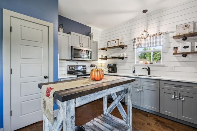 kitchen with dark hardwood / wood-style flooring, gray cabinetry, stainless steel appliances, sink, and hanging light fixtures