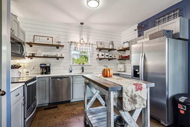 kitchen featuring gray cabinetry, sink, stainless steel appliances, and decorative light fixtures