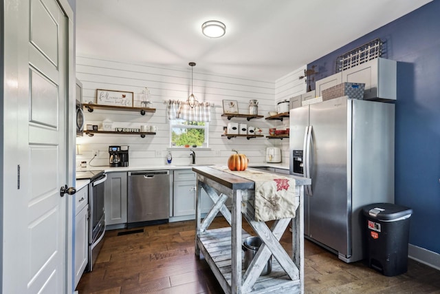 kitchen with decorative backsplash, dark hardwood / wood-style flooring, stainless steel appliances, sink, and decorative light fixtures