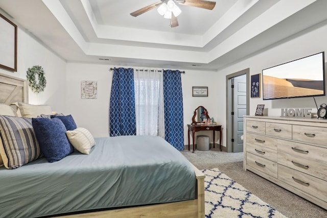 carpeted bedroom with a tray ceiling and ceiling fan