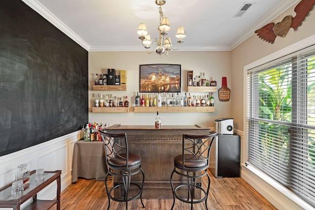 bar with crown molding, hardwood / wood-style floors, decorative light fixtures, and an inviting chandelier