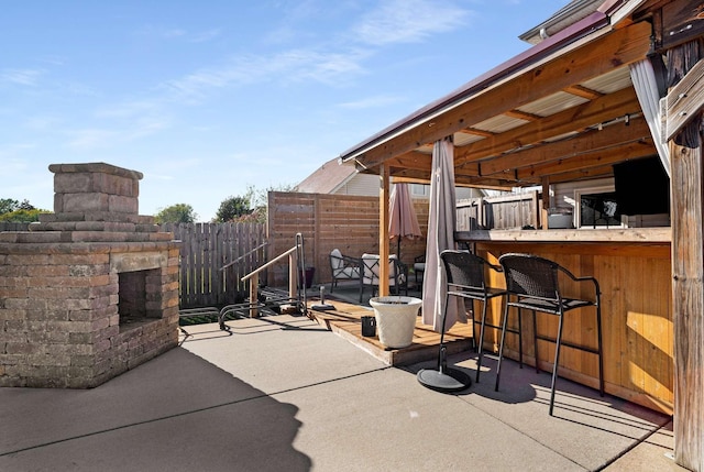 view of patio with an outdoor stone fireplace and a bar