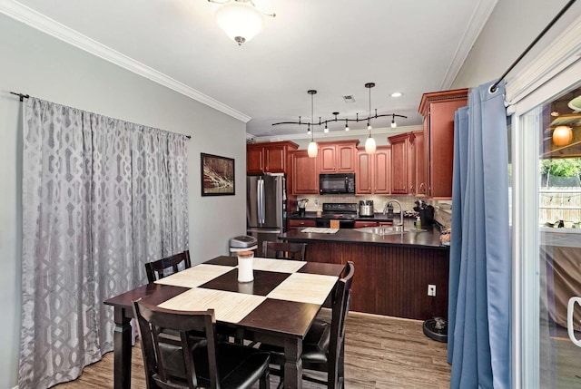 dining room featuring light wood-type flooring, ornamental molding, and sink