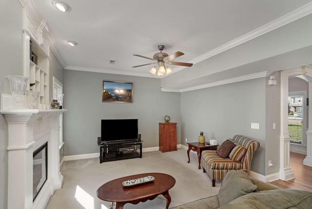 carpeted living room with ornate columns, ceiling fan, and crown molding