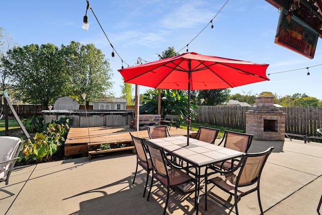 view of patio / terrace with a hot tub, exterior fireplace, and a deck