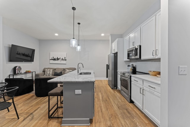 kitchen featuring stainless steel appliances, white cabinetry, a kitchen island with sink, and sink