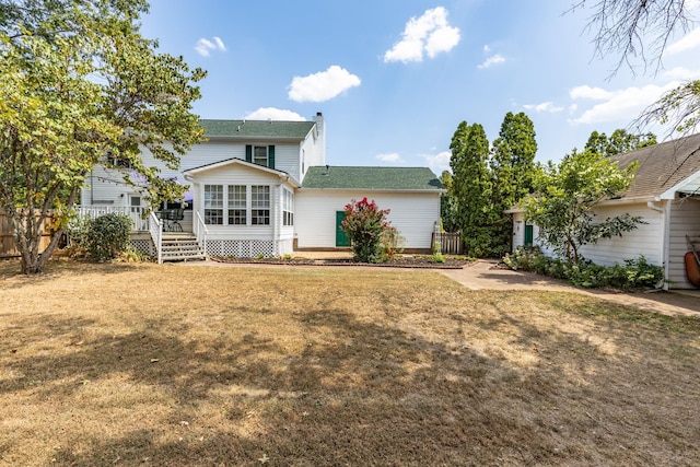 rear view of house featuring a wooden deck and a yard