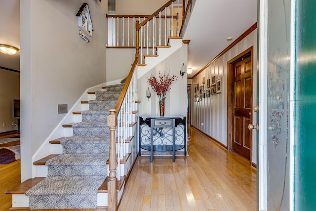 staircase with ornamental molding and hardwood / wood-style floors