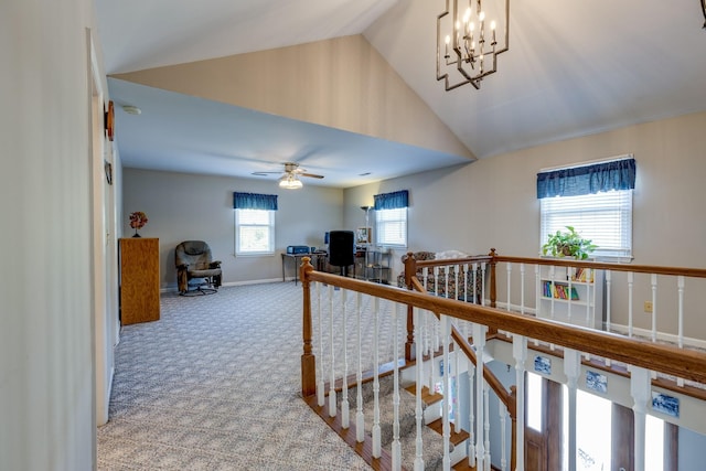 hall with vaulted ceiling, a chandelier, and carpet floors