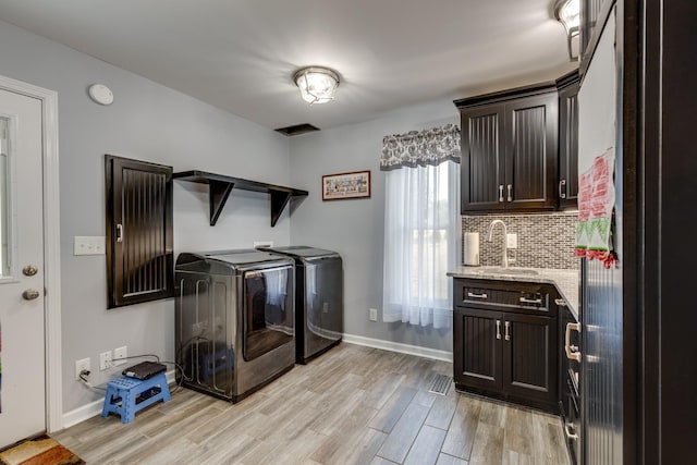 clothes washing area featuring sink, light hardwood / wood-style flooring, and independent washer and dryer