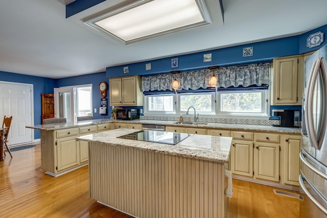 kitchen featuring sink, a center island, light hardwood / wood-style flooring, kitchen peninsula, and black appliances