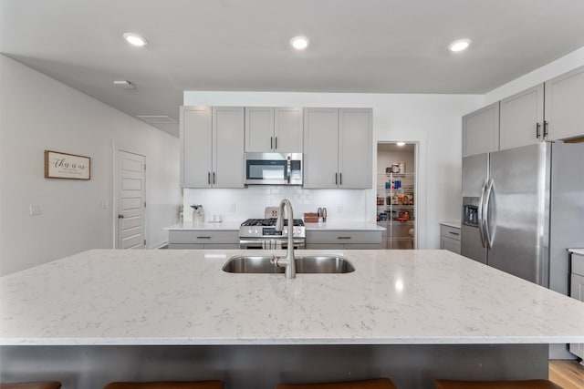 kitchen with a breakfast bar, appliances with stainless steel finishes, gray cabinetry, and sink