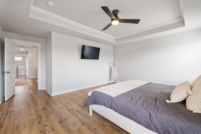 bedroom featuring ceiling fan, light wood-type flooring, and a tray ceiling