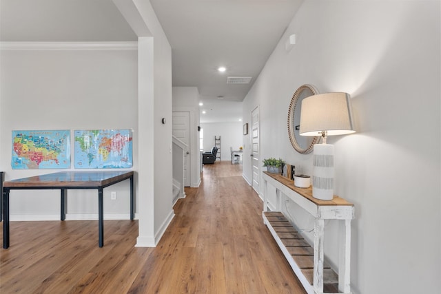 corridor featuring ornamental molding and light hardwood / wood-style flooring