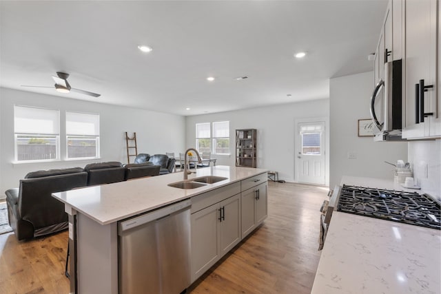 kitchen featuring gray cabinetry, a kitchen island with sink, sink, ceiling fan, and appliances with stainless steel finishes