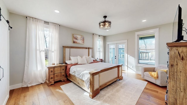 bedroom featuring a barn door and light hardwood / wood-style flooring