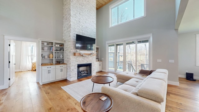 living room with a fireplace, a towering ceiling, and light hardwood / wood-style flooring