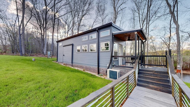 view of side of property with a wooden deck, ceiling fan, and a yard