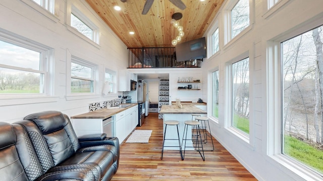 kitchen with appliances with stainless steel finishes, light wood-type flooring, wood ceiling, pendant lighting, and white cabinetry