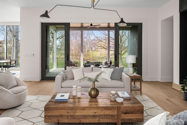 living room with ceiling fan, plenty of natural light, and light hardwood / wood-style flooring