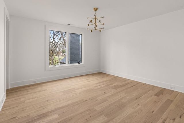 unfurnished room featuring an inviting chandelier and light wood-type flooring