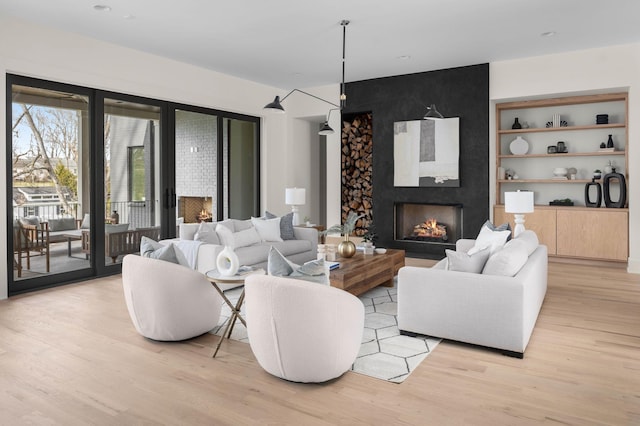 living room featuring a large fireplace, light hardwood / wood-style floors, and built in shelves