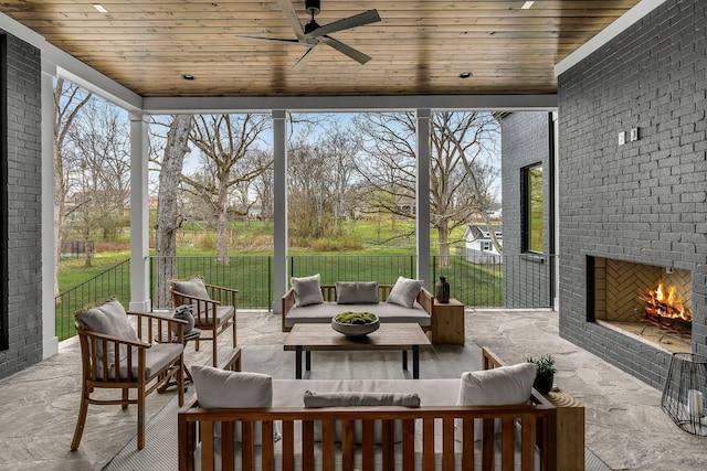 sunroom / solarium featuring an outdoor brick fireplace, a healthy amount of sunlight, and wooden ceiling