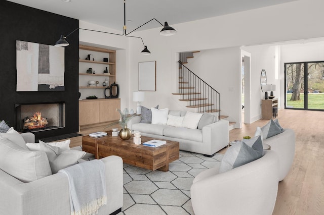 living room featuring a large fireplace, built in features, and light wood-type flooring